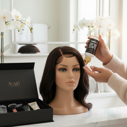 Amari Magic Glow lace front glue bottle being applied to a wig on a mannequin head. Black box present.